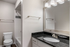 Modern bathroom featuring sleek black granite countertops, stylish lighting, and a pristine bathtub.