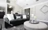 Chic living room featuring a sleek black leather sofa, elegant gray ottoman, and modern decor for a stylish, cozy ambiance.