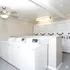 Bright and modern laundry room featuring multiple white washing machines and dryers, ideal for apartment living.