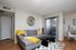 Charming living area with a cozy gray sectional sofa, bright yellow accents, and an inviting balcony view, perfect for relaxation.