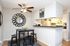Chic dining area with modern decor, featuring a stylish black table, eye-catching wall mirror, and sleek breakfast bar leading to a bright kitchen.