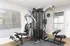 Modern home gym featuring a multifunctional exercise machine with sleek design, large windows providing ample natural light, and a stylish clock on the wall.