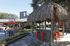 Inviting outdoor space featuring a charming thatched-roof gazebo with bright orange stools and vibrant red umbrellas, perfect for entertaining and relaxation.
