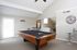Inviting game room with a sleek billiards table, modern decor, and ample natural light.