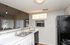 Modern kitchen with a sleek design featuring a stylish countertop, dual sink, and microwave. Illuminated 'EAT' sign adds charm to this inviting space.