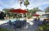 Charming outdoor oasis featuring a sparkling pool surrounded by lush greenery and vibrant red umbrellas for a perfect relaxation retreat.