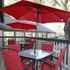 Charming outdoor patio with vibrant red umbrellas and sleek black chairs, perfect for relaxing in style.