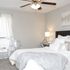 Elegant bedroom with plush bedding, soft gray tones, and a stylish acrylic chair, perfect for a serene retreat.