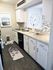 Charming modern kitchen with white cabinetry, decorative backsplash, and sleek countertops, featuring cozy decor and a large wall clock.