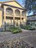 Charming apartment building with elegant arched balconies, lush landscaping, and inviting pathways.