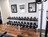 Modern apartment gym with sleek dumbbell rack, mirrors, and polished wood flooring.