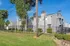 Charming apartment building with modern gray exterior, lush greenery, and secure fenced yard.