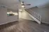 Modern open-concept living space with sleek hardwood floors, a stylish ceiling fan, and a cozy kitchen with bar seating.