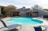 Inviting outdoor pool area with modern sun loungers and stylish wooden canopy, perfect for relaxation and leisure.