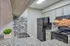 Modern kitchen with sleek granite countertops, stainless steel sink, and stylish tile backsplash, complete with a contemporary stove and spacious fridge.