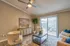 Inviting living room with elegant decor, featuring a ceiling fan, cozy seating, and large windows offering ample natural light.
