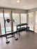 Sunny apartment gym with modern workout equipment, featuring a weight rack and exercise station in a bright, inviting setting.