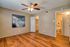 Inviting bedroom with elegant hardwood floors, modern ceiling fan, and contemporary artwork; ample closet space and an accessible bathroom nearby.