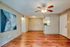 Inviting open-concept living space with warm wooden floors, contemporary ceiling fan, and stylish artwork, perfect for cozy gatherings.