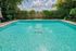 Inviting outdoor swimming pool surrounded by lush greenery, offering a serene retreat with a crystal-clear water experience.