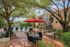 Charming outdoor patio with red umbrella, inviting seating area, and a sparkling pool surrounded by lush greenery.