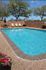 Charming outdoor pool area with crystal-clear water, surrounded by stylish lounge chairs and vibrant flowers, perfect for relaxation.