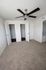 Bright bedroom featuring dual closets, plush carpet, and a sleek ceiling fan.