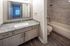 Modern bathroom featuring a sleek granite countertop and elegantly tiled shower area, exuding luxury and comfort.