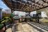 Charming outdoor patio with pergola, built-in grills, and lush greenery, perfect for entertaining.