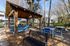 Inviting outdoor area with a wooden gazebo, modern lounge chairs, and a stylish dining set amidst lush greenery.