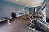 Modern fitness center with state-of-the-art cardio machines, weight bench, and free weights in a spacious, well-lit room.