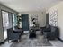 Chic apartment lounge with elegant gray chairs, modern art, and abundant natural light.