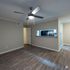 Modern apartment interior featuring sleek wood flooring, a cozy ceiling fan, and an open pass-through to a stylish kitchen with contemporary finishes.