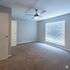 Bright and airy bedroom with plush carpeting, modern ceiling fan, and large window with blinds.