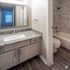 Elegant bathroom featuring a granite countertop, modern vanity, and luxurious bathtub with stylish tile accents.