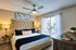 Elegant bedroom with plush tufted headboard, sleek ceiling fan, and large window offering ample natural light and a cozy ambiance.
