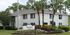 Charming Hunters Pointe apartment complex with elegant white brick facade surrounded by lush greenery and palm trees.