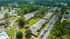 Expansive aerial view of a charming apartment complex surrounded by lush greenery, featuring ample parking and a serene community setting.