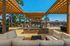 Inviting outdoor lounge area with stylish pergolas and a central stone fireplace, creating a perfect setting for relaxation or entertaining guests on a sunny day.