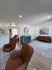 Modern living room with elegant brown leather chairs, plush area rug, and stylish wall art, offering a cozy and inviting atmosphere.