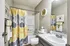 Bright, modern bathroom featuring a chic floral shower curtain, stylish wall clock, and elegant countertop, creating a refreshing and inviting atmosphere.