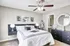 Bright and inviting bedroom with modern decor, featuring a comfortable bed, artistic wall art, and an elegant ceiling fan.