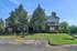 Charming apartment building surrounded by lush greenery and a spacious parking area, perfect for a serene and convenient living experience.
