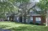 Charming apartment complex nestled in lush greenery, featuring modern two-story architecture and large windows.