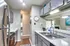 Modern kitchen featuring stainless steel appliances, sleek grey cabinets, and elegant stone countertops, leading to a bright open-concept living area with stylish decor.