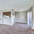 Inviting open-plan living room with plush carpet and natural light, featuring a cozy kitchen nook and sliding glass doors to a balcony.