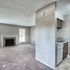 Inviting apartment interior featuring a cozy living room with a fireplace and plush carpeting, adjacent to a modern kitchen with sleek cabinetry.