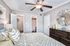 Chic bedroom with elegant ceiling fan, stylish mirror decor, and inviting bedding, exuding modern comfort.