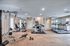Spacious and well-equipped apartment fitness center with modern cardio machines, weight equipment, and bright natural lighting.