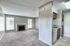 Bright and spacious living room with plush carpeting, featuring a cozy fireplace and ample natural light. Adjacent kitchen area includes modern appliances and sleek cabinetry.